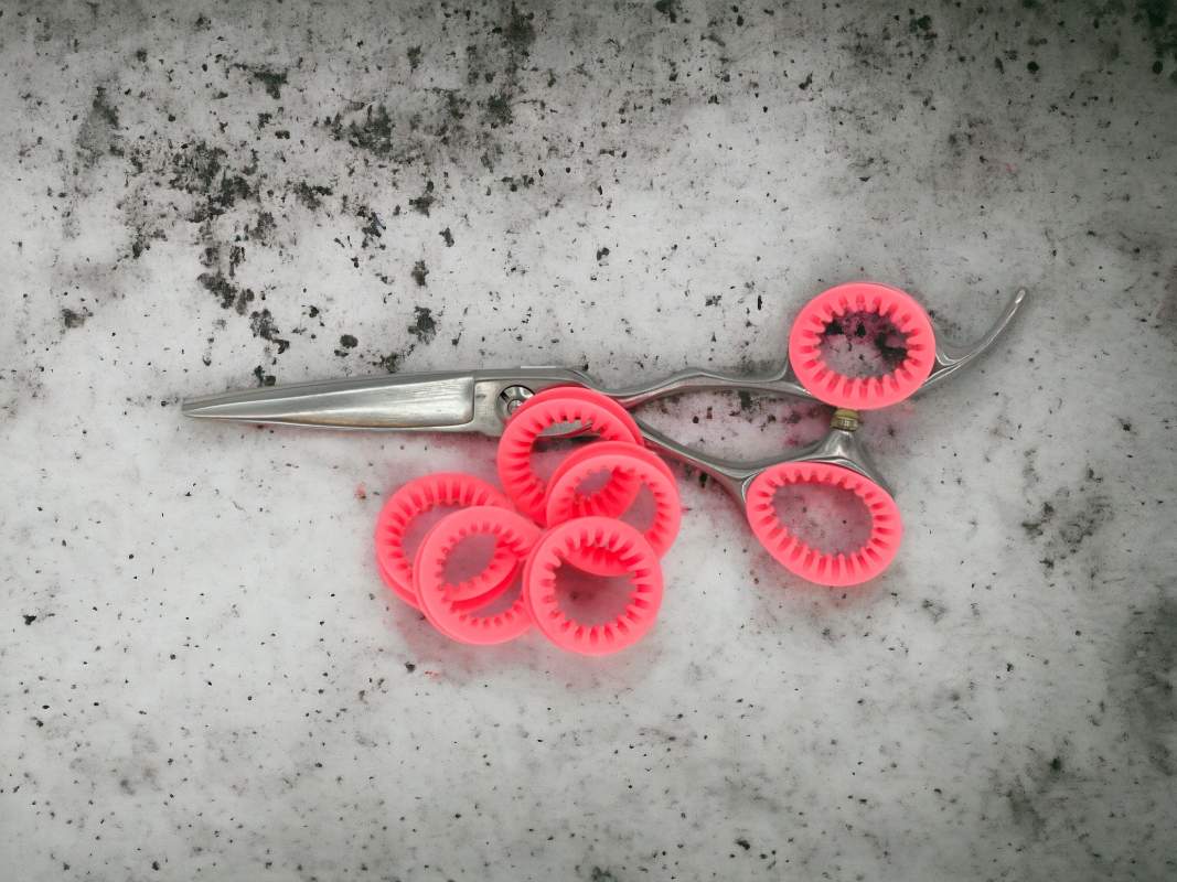 Set of Coral Pink ShearRIngs in a pair of haircutting shears on a concrete background