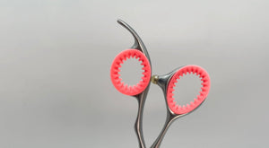 A pair of coral pink ShearRings inside a pair of haircutting shears 